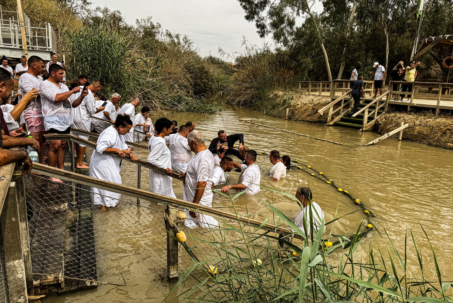 With clergies’ assistance, hundreds of Christians daily take a baptismal dunk in the Israeli-controlled West Bank of the Jordan River; John baptized Jesus on the Jordanian side.
