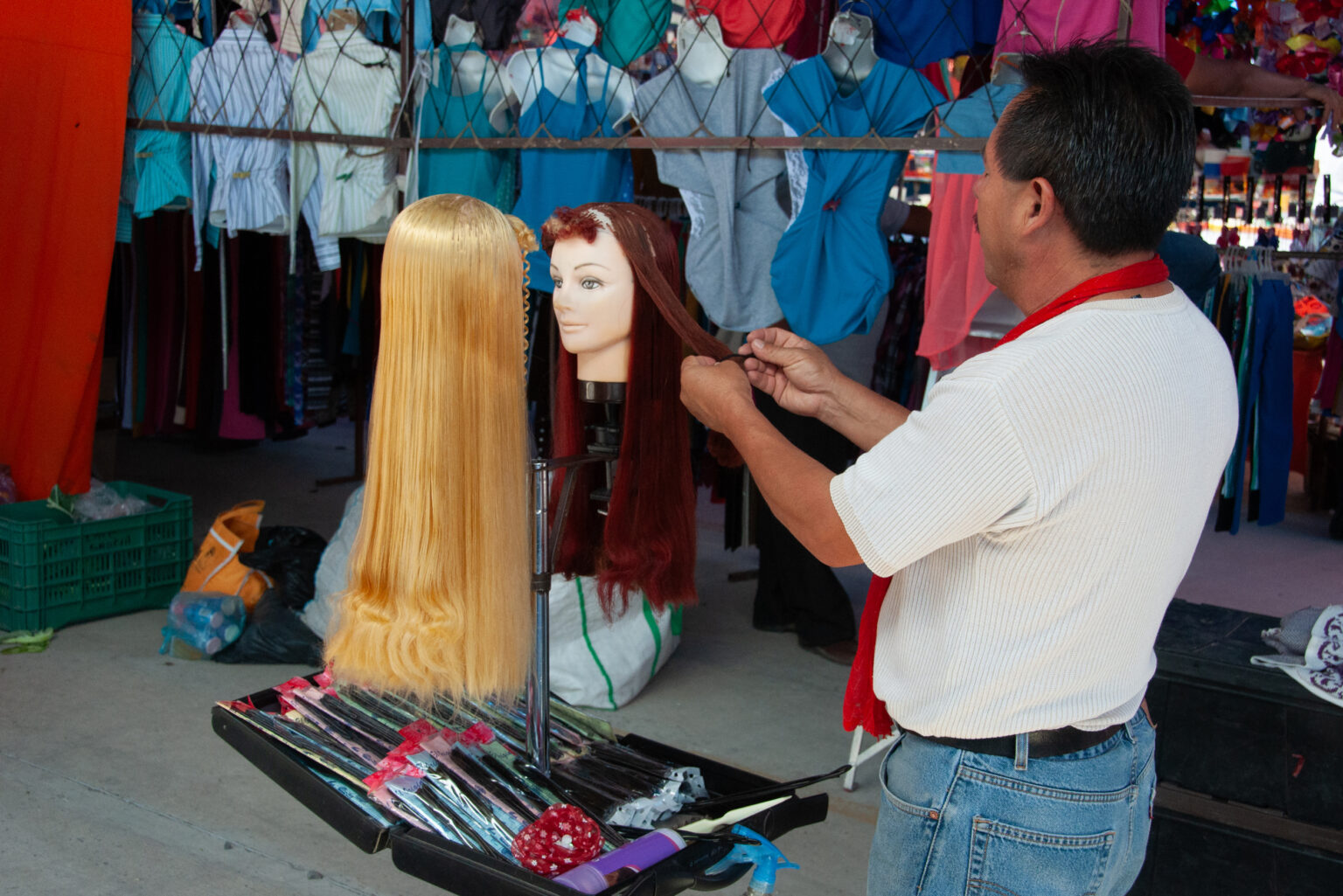 A merchant styles wigs at his stall