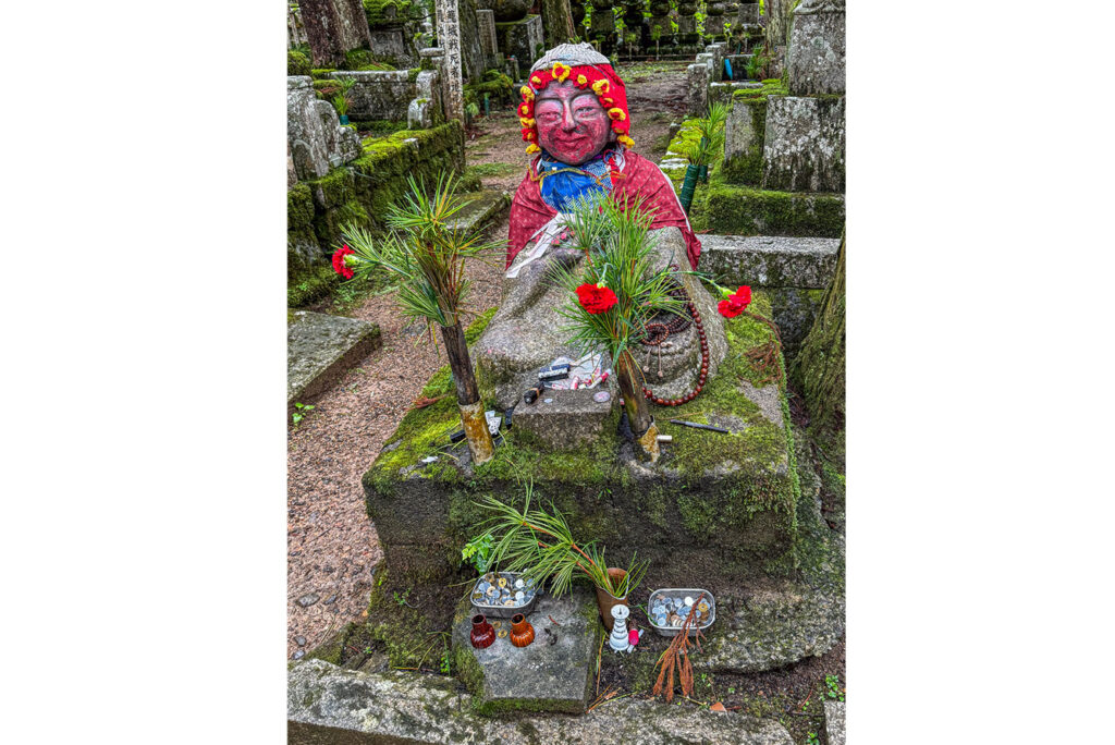Families and friends dress stone images for cold weather at Okunoin Cemetery